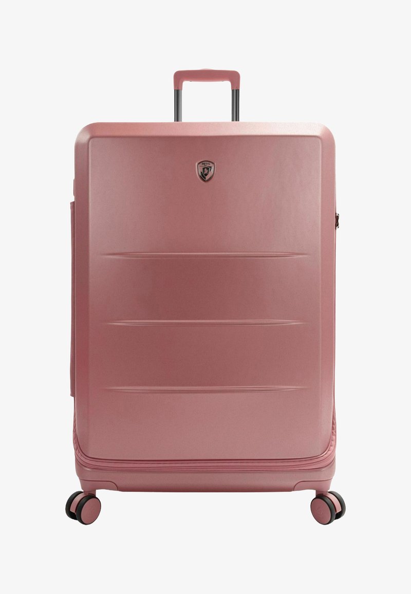 Rosa Hartschalenkoffer mit glatter Oberfläche, horizontalen Rillen, Teleskopgriff und vier schwarzen Rädern. Ausgestattet mit einem metallischen Logo-Emblem.
