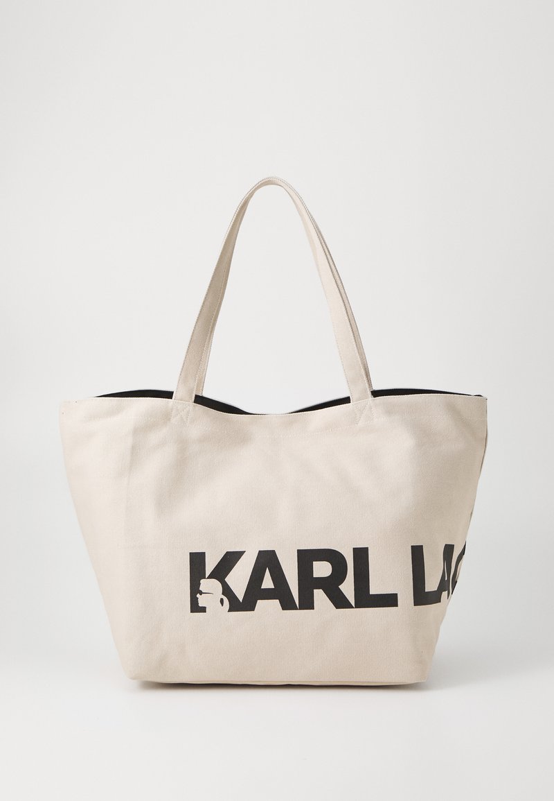 Beige Canvas-Shopper mit schwarzem Logo-Text "KARL LAGERFELD" und einem schwarzen Akzent am oberen Rand. Verfügt über zwei Schulterriemen.