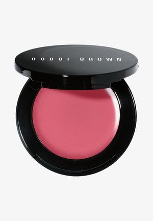 Kremowy róż Bobbi Brown w okrągłym czarnym pudełku o błyszczącym wykończeniu, z miękkim różowym produktem w środku.