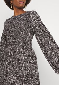 Schwarzes Blumenkleid mit langen Puffärmeln, gerafftem Bund und kleinem weißen und rosa Blumenmuster überall. Glatte Stofftextur.
