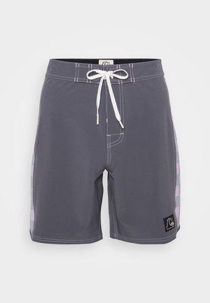 Graue Badehorts mit weißem Kordelzug, mit weißen Nähten und einem schwarzen Logo-Patch. Die Seite hat einen gemusterten Akzent inHelllila.