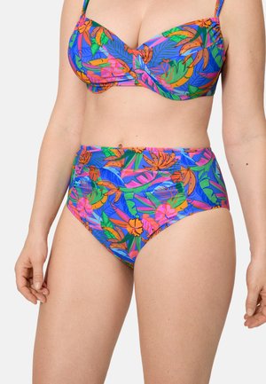 Mujer vistiendo un traje de baño de dos piezas con un patrón floral tropical colorido, que incluye un top con relleno y pantalones de talle alto.