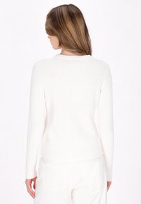 Maglione bianco a nido d'ape con maniche lunghe e orlo a coste. La parte posteriore presenta un motivo testurizzato e un collo rotondo. Tessuto morbido.