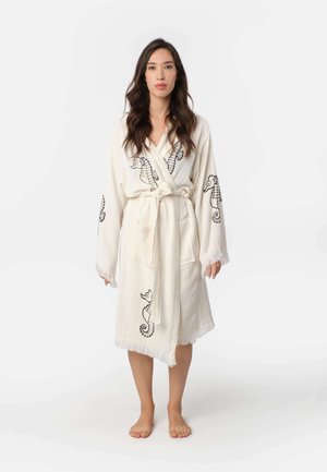 Witte stoffen robe met zwarte zeepaardjes borduursels, voorzien van een strikceintuur, lange mouwen en franjes aan de zoom.