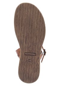 Ruskea kumipohja, jossa on pystysuorat urat. Varustettu leimatulla logolla ja kokomerkinnällä. Pyöreä muoto ja sileä pinta.