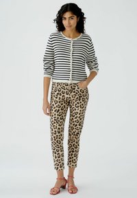 Gestreifter Cardigan in Marineblau und Creme, mit Knopfverschluss; kombiniert mit beigen Leopardenmuster-Hosen; rote Blockabsatzsandalen.