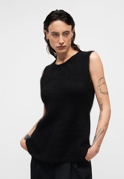 Μαύρος αμάνικος πουλόβερ από μαλακό, χνουδωτό ύφασμα. Διαθέτει στρογγυλή λαιμόκοψη και άνετη γραμμή με πλαϊνές τσέπες. Ομαλή υφή.
