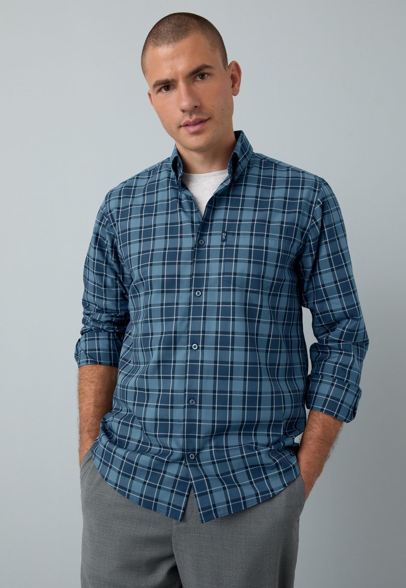 Blau kariertes Hemd mit Kragen und durchgehender Knopfleiste, das verschiedene Schattierungen von Blau und Grau zeigt und langärmlig ist mit hochgekrempelten Manschetten.