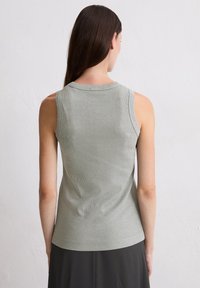 Jasnozielony bezrękawnik o rypsowym wzorze, okrągłym dekolcie i dopasowanym kroju, widok z tyłu. Minimalistyczny design.
