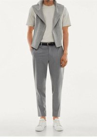 Jasnoszary bezrękawnik na białej koszulce, zestawiony z jasnoszarymi, dopasowanymi spodniami i białymi trampkami, o gładkiej fakturze.