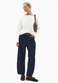 Biała wełniana sweter, ciemnoniebieskie szerokie spodnie dżinsowe, brązowe buty na sznurówki i brązowa torba w panterkę z paskiem na ramię.