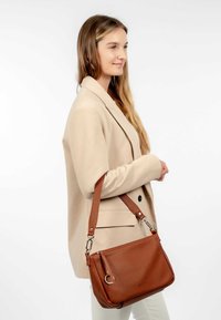 Sac à épaule en cuir brun avec une finition texturée, fermeture zippée et quincaillerie décorative. Bandoulière ajustable et design spacieux.