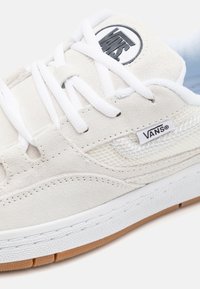 Tenisi VANS din suede alb și plasă cu șireturi albe. Au un logo rotund, o talpă texturată și o talpă din cauciuc de tip gum pentru aderență.