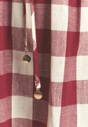 Tela a cuadros roja y blanca con apariencia de lino texturizado. Presenta un cordón con un acento circular dorado en el extremo.