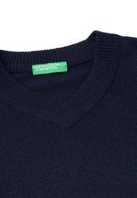 Suéter azul marino de cuello en V hecho de un suave tejido de punto. Presenta un cuello acanalado y una etiqueta verde que dice "UNITED COLORS OF BENETTON."
