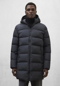 Kurtka puchowa w jednolitym czarnym kolorze, z zamkiem błyskawicznym z przodu, kapturem i pikowaną konstrukcją. Gładka tekstura z poziomymi przeszyciami i kieszeniami po bokach.