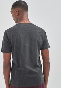 Tumehall hall retro tee, mis on valmistatud pehmest kangast, klassikalise ümmarguse kaelusega ja lõdva lõikega, sujuva tekstuuri ja nähtavate mustriteta.