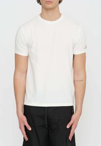 T-shirt bianco a maniche corte in tessuto morbido e leggero. Design con colletto rotondo e piccolo dettaglio del logo sulla manica sinistra.