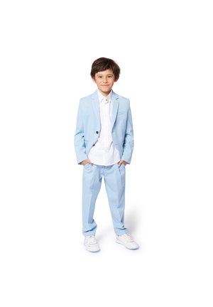 Costume bleu clair avec une veste à un bouton, chemise blanche et pantalon ajusté assorti. Porté avec des baskets blanches. Design simple et lignes épurées.