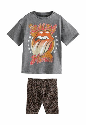 Šedé tričko s krátkým rukávem s grafikou Rolling Stones; hnědé legíny se zvířecím potiskem leopardí kůže a elastickým pasem.