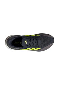 Baskets noires de sport avec une tige texturée et des accents verts. Présente un design à lacets et une semelle légère et rembourrée.
