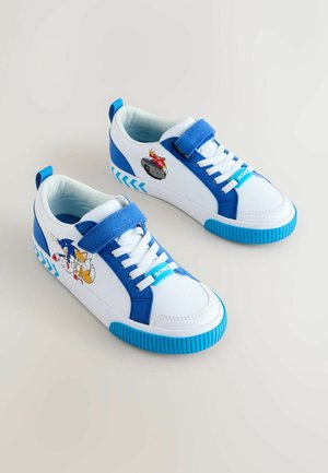 Fehér sportcipők kék részletekkel, oldalán rajzfilmfigurás mintákkal, texturált gumitalppal és tépőzáras pánttal.