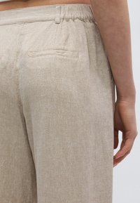 Μπεζ λινό παντελόνι με υφή υφάσματος, διαθέτει άνετη εφαρμογή, ελαστική μέση και δύο πίσω τσέπες.