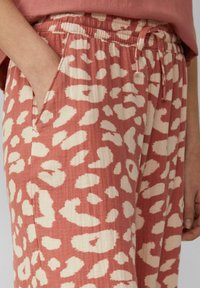 Leopardenmuster-Jogginghosen in Terracotta und Creme, mit einem elastischen Bund, seitlichen Taschen und einer entspannten Passform.