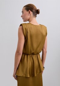 Olivgrünes, ärmelloses Blusenshirt mit entspanntem Schnitt und gerafftem Bund. Weicher, strukturierter Stoff mit einem dezenten Glanz und Rundhalsausschnitt.
