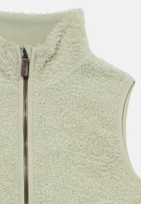 Φωτεινό πράσινο γιλέκο φλις με υφή στην επιφάνεια, ψηλό γιακά και πλήρες φερμουάρ μπροστά. Διαθέτει αντιθετικές λείες άκρες.