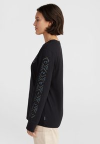 Black long-sleeve shirt in cotton with geometric patterns in teal along the sleeves. Crew neck and relaxed fit. Classic design for casual wear.