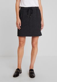 Jupe noire arrivant aux genoux, fabriquée en tissu texturé avec une ceinture élastique et un cordon de serrage ; dotée de poches latérales pour plus de praticité.