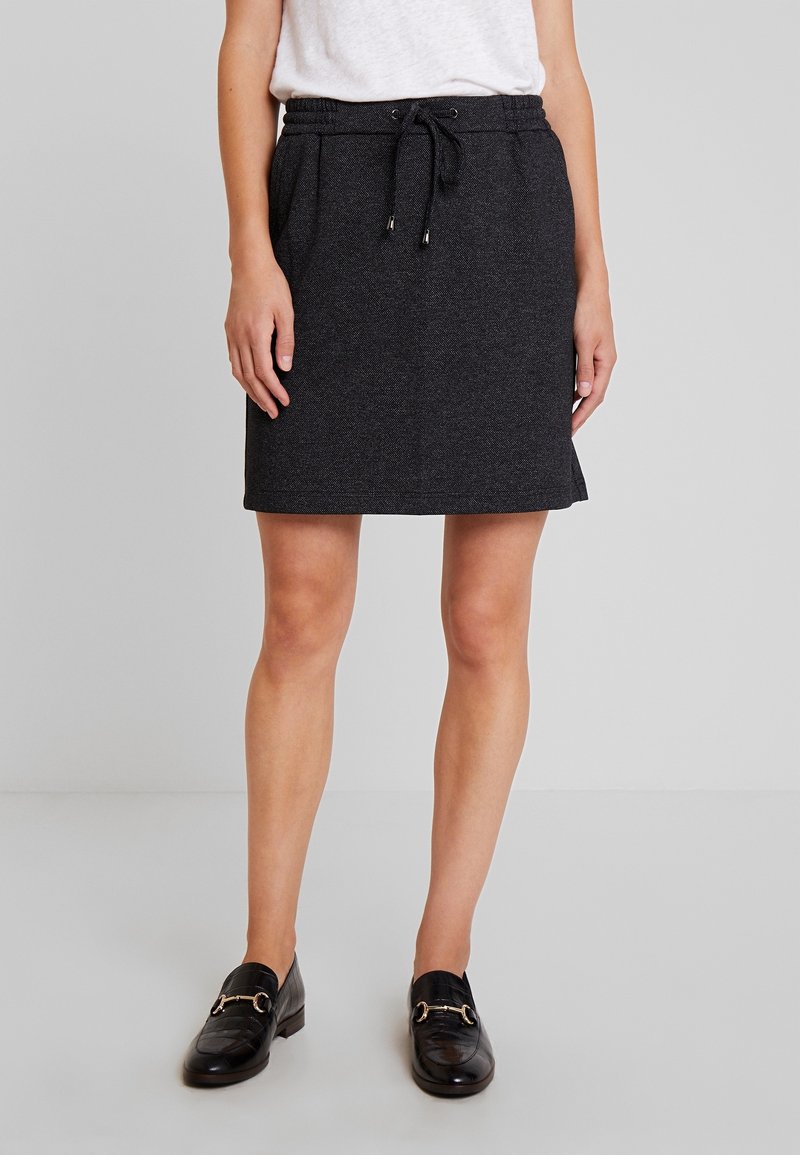 Jupe noire arrivant aux genoux, fabriquée en tissu texturé avec une ceinture élastique et un cordon de serrage ; dotée de poches latérales pour plus de praticité.