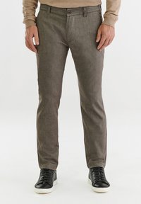 Szare, teksturowane spodnie o slim fit, z pojedynczym zapięciem na guzik i bocznymi kieszeniami, zestawione z czarnymi sneakersami.