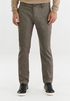 Szare, teksturowane spodnie o slim fit, z pojedynczym zapięciem na guzik i bocznymi kieszeniami, zestawione z czarnymi sneakersami.