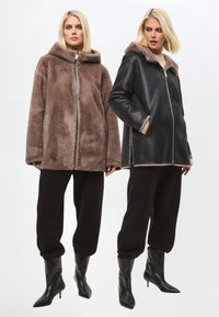 Dos chaquetas exhibidas: un abrigo con capucha de piel sintética marrón y un abrigo negro de cuero con cremallera y forro de piel, combinado con pantalones y botas negras.