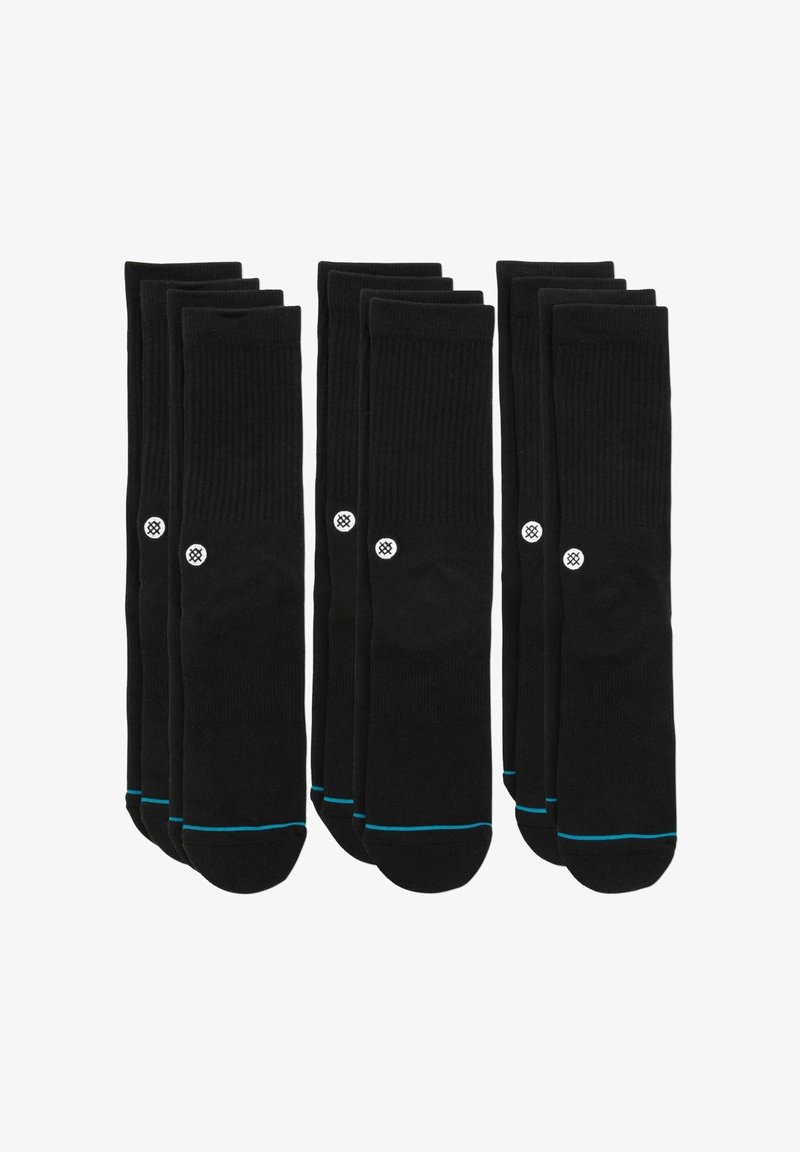 Calcetines de algodón negros, con textura acanalada, que presentan un logo blanco y un ribete azul en la parte superior. Conjunto de múltiples pares dispuestos en filas.