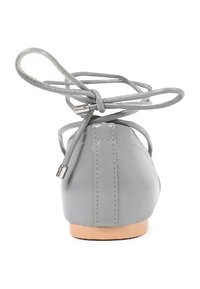 Bailarinas de cuero gris con punta redondeada y cordones entrelazados en la parte posterior. Presentan una textura suave y una suela de madera clara.