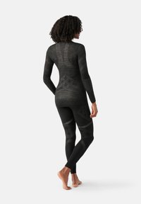 Leggings noirs et haut à manches longues en matériau texturé avec un motif géométrique dans différentes nuances de gris. Design ajusté.