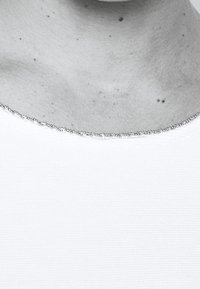 Top bianco con scollatura rotonda, caratterizzato da un bordo decorato con perline argentate. Leggera texture visibile nel tessuto.