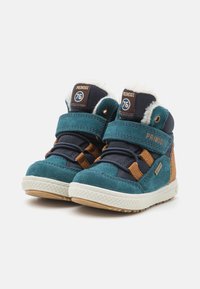 Bottes montantes teal et marine avec des accents marron, en suede texturé, semelle en caoutchouc, bandes Velcro et doublure en fausse fourrure blanche au niveau du col.
