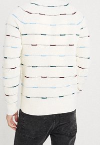 Maglione color crema con righe orizzontali multicolori in blu, verde e bordeaux. Colletto e polsini a coste. Tessuto lavorato a maglia.