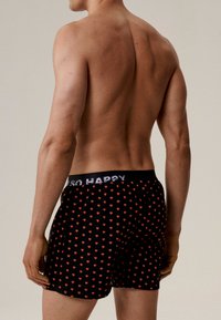 Czarne bokserki w czerwony wzór serca, z elastycznym pasem z napisem "SO HAPPY" oraz dopasowanym fasonem.