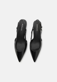 Juodos lakinės odos slingback kulniukai su smailiu nosiu, turintys sklandų užbaigimą ir reguliuojamą dirželį, užtikrinantį tvirtą prigludimą.
