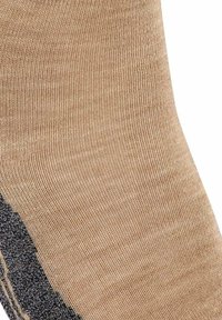 Beige sok med en glat tekstur, der har et ribbet design og en sort detalje nær bunden, hvilket giver kontrast og visuel dybde.