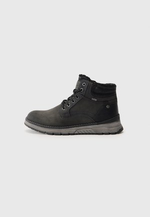 Botas negras hasta el tobillo con un exterior de cuero suave, acentos texturizados y un interior de suave pelaje. Presentan una suela de goma gruesa y un sistema de cierre con cordones.