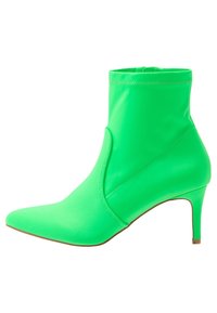 Zelené kotníkové boty s hladkým povrchem, špičatou špičkou a štíhlým podpatkem. Vyznačují se těsným úchopem kolem kotníku a prošitými detaily.