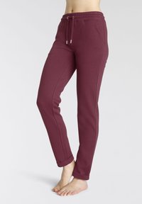 Bordeauxfarbene Jogginghose aus weichem Material, mit einem elastischen Bund und Kordelzug, sowie seitlichen Taschen. Enganliegende Bündchen an den Knöcheln.