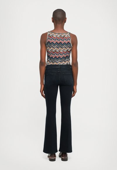 Woven tank top with zigzag pattern in multi-colors, paired with dark blue flared jeans and brown platform sandals.