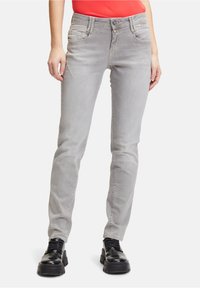 Grå tajta jeans med fem fickor, i en något blekt tvätt, med knäppning framtill och kontrasterande sömmar. Kombineras med svarta kraftiga skor.